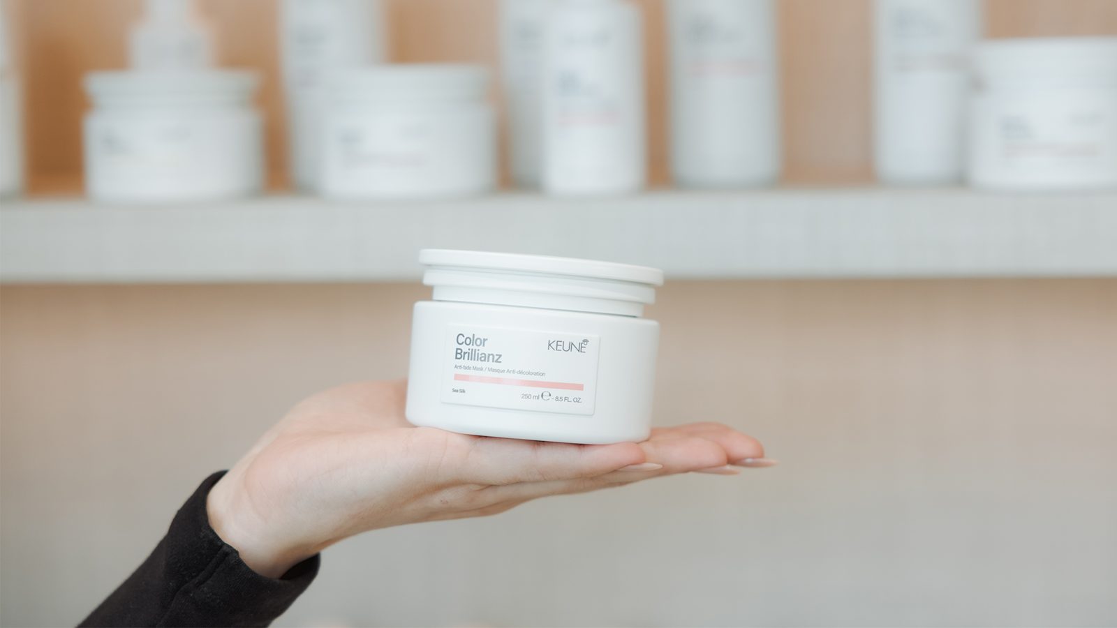 Hand die de Keune Color Brillianz Anti-fade Mask in het grote formaat vasthoudt