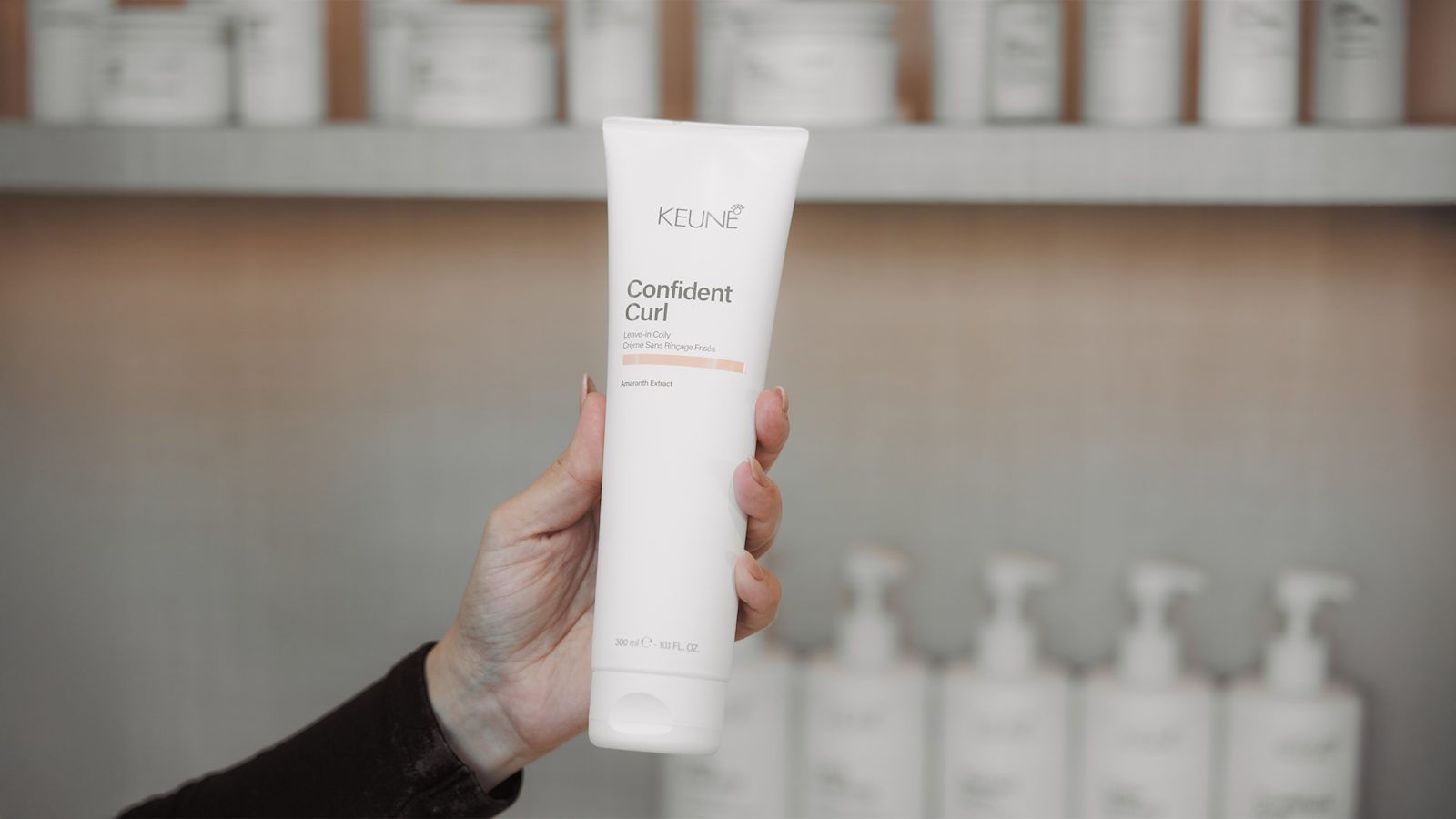 Hand met de Keune Confident Curl Leave-in Coily 300 ml